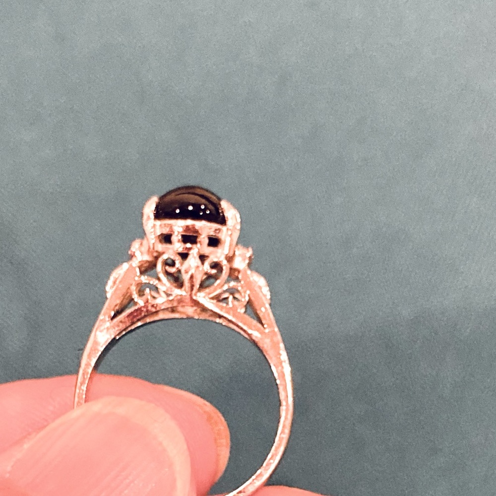 Silver-tone ring with filigree and black cabochon centre.